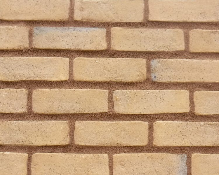 A display panel of brick slips. The bricks are a pale yellow colouration with a sandy surface. The bricks are pointed in a mid brown sandstone pointing mortar