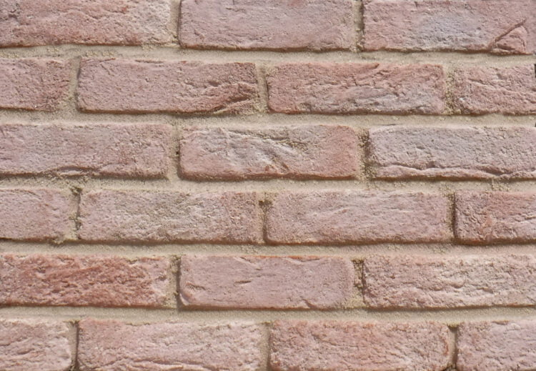 A display panel of pink brick slips. The bricks are have a sandy, riven surface texture. The bricks are pointed with a light sandstone mortar.