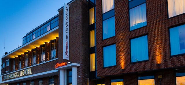 Hampton by Hilton Park Royal Hotel in London at dusk. The new signage and extension are glowing in the low light conditions but the warm, aged brick slips look magnificent